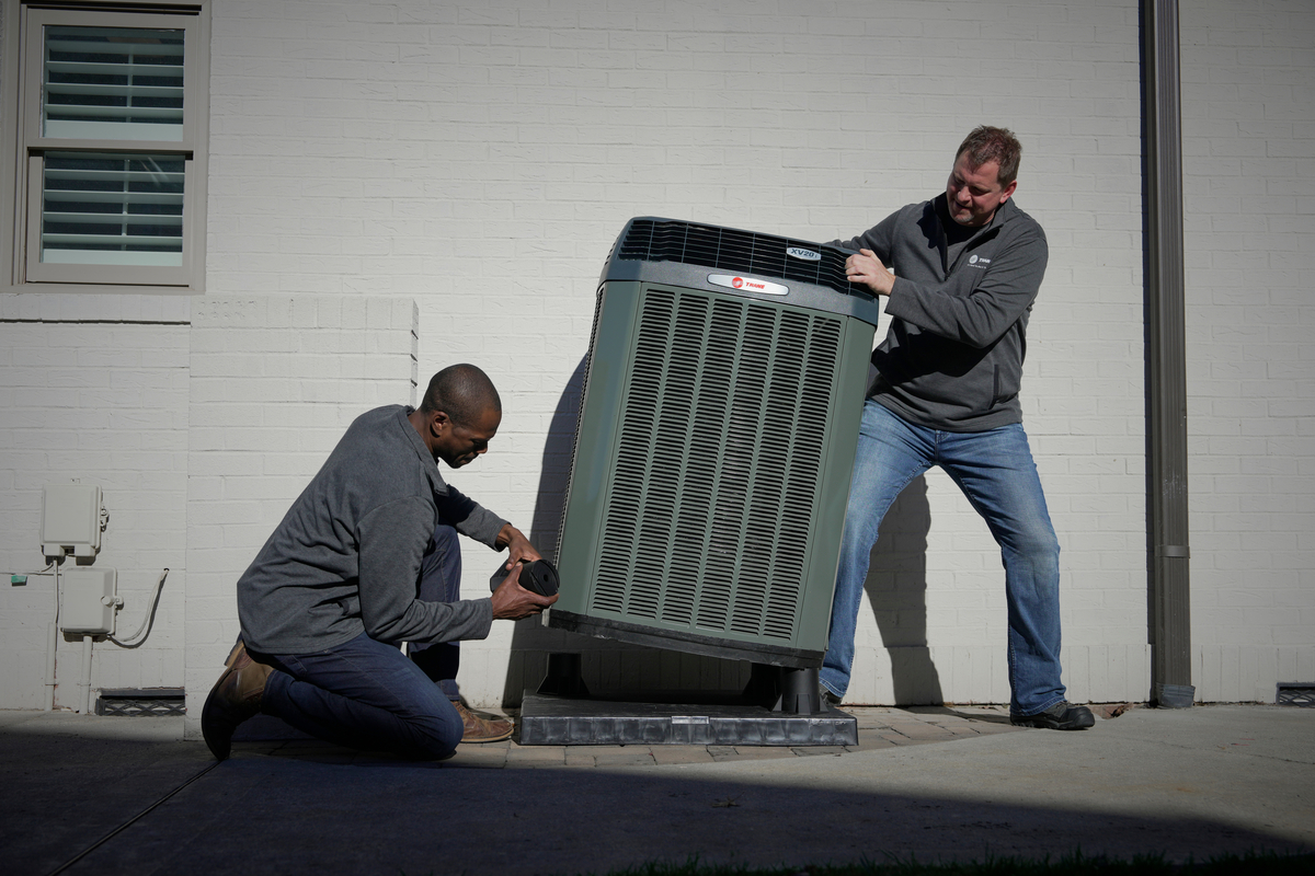 Two HVAC technicians servicing outdoor unit